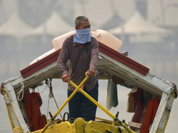 Pengusaha perahu tambang, Jeni Boh, 54, mengayuh perahunya di Sungai Sarawak berhampiran Tebingan Sungai Kuching di Kuching, Sarawak untuk mengambil penumpang. - Foto Bernama 