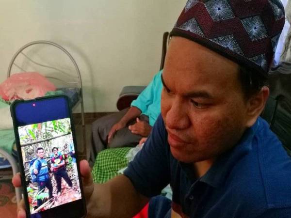 Nasir menunjukkan gambar arwah Muhammad Izzat Faqih (kiri).