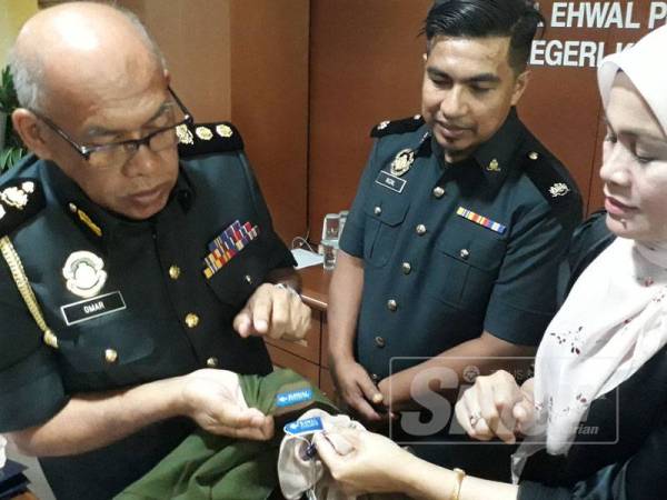 Omar (kiri) mendengar penerangan dari Pengarah Pemasaran Bawal Exclusive Sdn Bhd, Haliza Maysuri (kanan) tentang perbezaan di antara tudung bawal exclusive original dan tiruan.