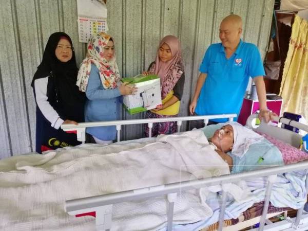 Che Nor Hayati (dua kiri) bersama Tiong Lam (kanan) menyerahkan penyedut kahak kepada Nur Fatin Shahira.