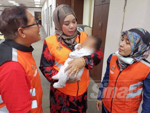 Dari kiri, Azmi dan Halimaton yang memangku bayi tersebut semasa tiba di Pejabat JKM Kedah di Anak Bukit, Alor Setar.