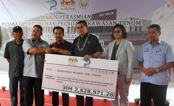 Salahuddin menyampaikan replika cek bernilai RM2.6 juta bagi kos pembinaan bangunan pejabat Pertubuhan Peladang Kawasan (PKK) Tenom. -Foto Bernama