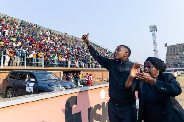 Anak lelaki Mugabe, Chatunga Mugabe (kiri) menyambut sorakan orang ramai yang berkumpul untuk melihat mayat bekas Presiden Zimbabwe di Stadium Rufaro. - Foto AFP