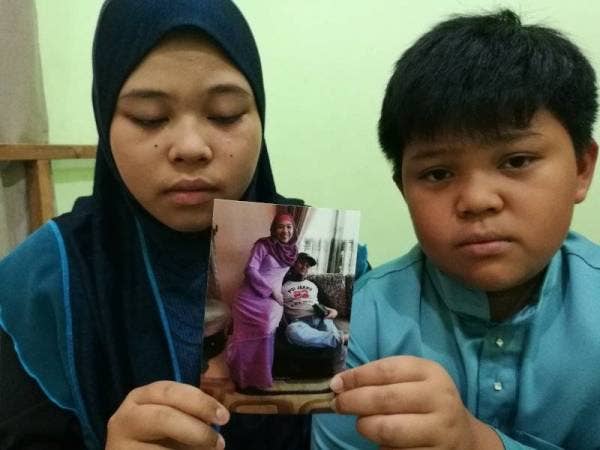 Nor Syazwany bersama adiknya, Muhammad Akmal menunjukkan gambar ibu dan bapa mereka.