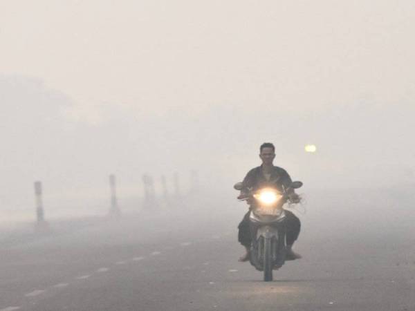 Seorang penunggang motosikal meredah jerebu tebal di Kampung Rambutan, wilayah Sumatra Selatan. - Foto AFP