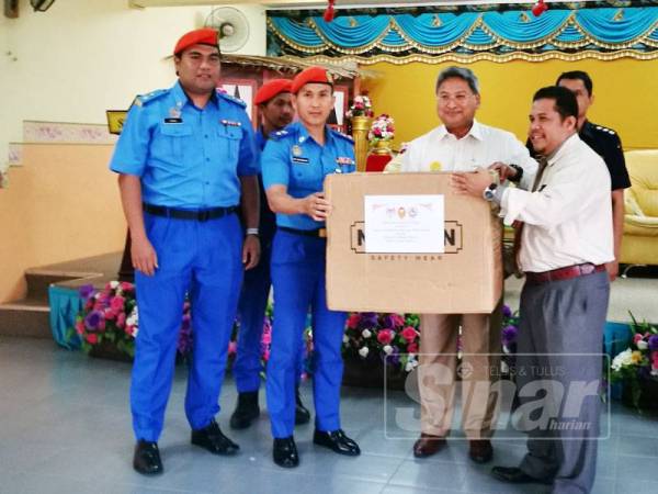Awang Iskandar (dua dari kiri) menyerahkan topeng muka kepada Mohd Yusri (dua kanan) di Sekolah Kebangsaan Sri Kulim hari ini.