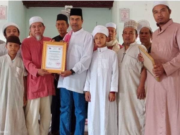 Mustapha menerima sijil perhargaan daripada Abd Manap sambil disaksikan penduduk Kampung Jamuan Sempadan.