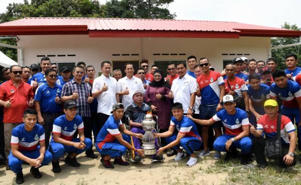 Peter Anthony bersama pemain bola sepak pasukan negeri itu serta Piala Liga Perdana pada majlis penyampaian kunci Rumah Program Perumahan Rakyat Termiskin (PPRT) kepada bekas pemain bola sepak Sabah Paulus Jimit, 57, di Kampung Seberang Tabilung, Tambunan hari ini.- Foto: BERNAMA
