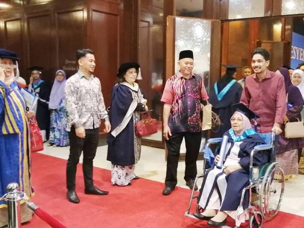 Wan Zainun yang berkerusi roda dibawa keluar daripada dewan oleh ahli keluarganya selepas berakhirnya sesi Majlis Konvokesyen ke-23 OUM di PWTC semalam. 