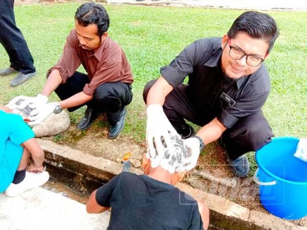 Faizul membersihkan kepala muridnya yang dijangkiti kutu.