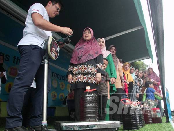 Kakitangan Alamflora menimbang berat minyak masak dari penduduk Apartment Fasa 7 pada program kutipan minyak masak terpakai oleh Alamflora di Apartment Fasa 7,Putrajaya. - Foto Sinar Harian/ZAHID IZZANI