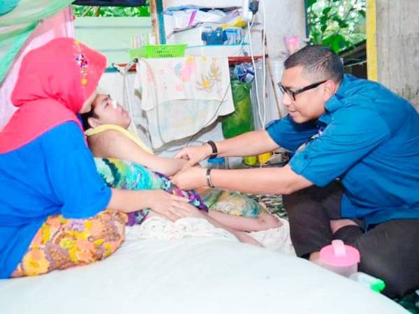 Mohd Syahbuddin menyampaikan sumbangan kepada Muhammad Syahir ketika berkunjung ke rumah keluarga itu di Kampung Lebur Jaya, Kuala Betis.