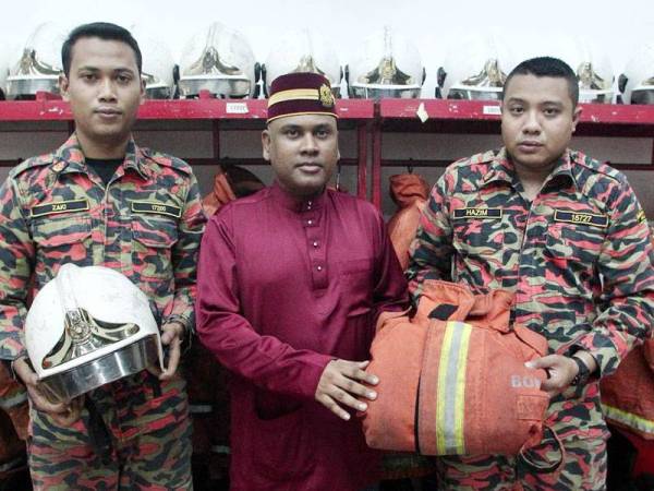 Syed Shahril Anuar (tengah) bersama Zaki dan Hazim menunjukkan helmet dan jaket keselamatan bomba yang digunakan Allahyarham Muhammad Adib. FOTO:ZAHID IZZANI