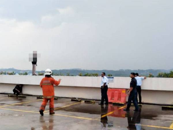 Anggota bomba berjaya memujuk seorang lelaki yang cuba untuk terjun dari tingkat tiga bangunan sebuah pasar raya di Seremban 2 di sini petang tadi. - FOTO: JBPM