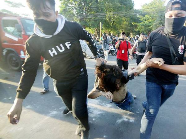 Polis menahan seorang pelajar semasa tunjuk perasaan di hadapan Kampus Universiti Hasanuddin di Makassar.