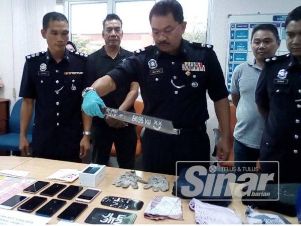 Mustafa memegang parang tertera perkataan 'terbaik bossku' yang digunakan dua suspek untuk menyamun premis pada sidang media di IPD Pontian di sini hari ini.