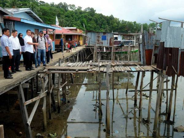 Menteri Pembangunan Infrastruktur Sabah Datuk Peter Anthony (empat, kiri) melihat keadaan jambatan yang menghubungkan rumah penduduk sewaktu mengadakan lawatan dan meninjau kemudahan asas yang terdapat di pulau itu hari ini. Turut hadir, Anggota Parlimen Sandakan, Vivian Wong Shir Yee (lima, kiri). - Foto Bernama