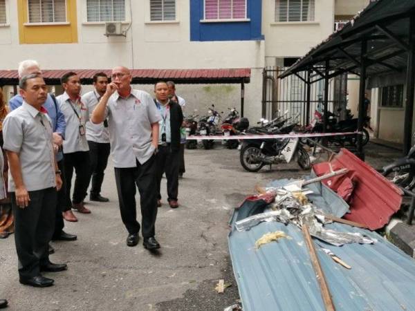 Nor Hisham (kanan) meninjau keadaan PPR Desa Rejang yang dilanda ribut pagi tadi.