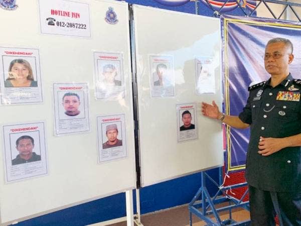 Hasanuddin (kanan) menunjukkan wajah 11 individu yang dikehendaki untuk membantu kes dadah sejak tahun lalu.