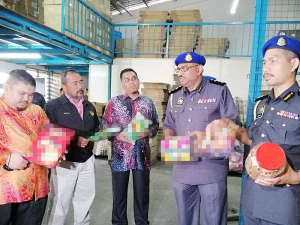 Ravichandran (dua dari kanan) dan Burhanuddin (tiga dari kanan) menunjukkan antara produk makanan ringan yang disita.