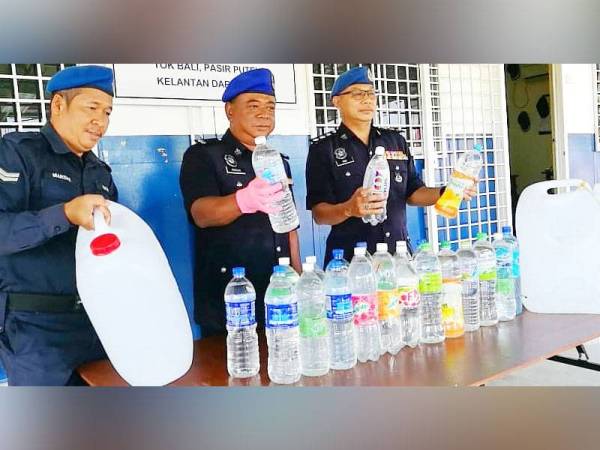 Mohd Razlin (tengah) menunjukkan arak buatan sendiri yang diisi ke dalam pelbagai jenis botol minuman bagi mengaburi pihak berkuasa.