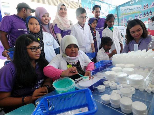 Pegawai Farmasi Provisional Hospital Tengku Ampuan Rahimah Klang, S Ceciwani (kiri) dan rakannya Steffie Desiree (kanan) membantu peserta cilik untuk menyediakan ubat ketika hadir pada Program Santuni Rakyat, Kenali Ubat Anda sempena Sambutan Hari Farmasi Sedunia Peringkat Kebangsaan 2019 di Dewan Datuk Penggawa Permatang, Kuala Selangor, hari ini. - Foto Bernama