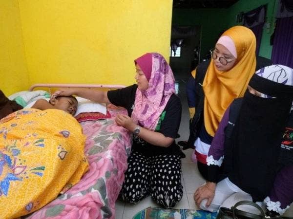 Nor Sakilawati (dua dari kiri) sedang mengelap kepala anaknya sambil diperhatikan oleh Maznah (kanan) di rumah mereka di sini hari ini.