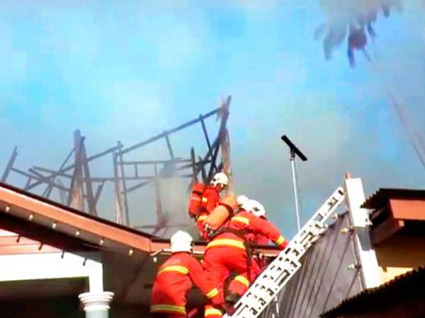 Anggota bomba berusaha memadamkan kebakaran daripada terus merebak.