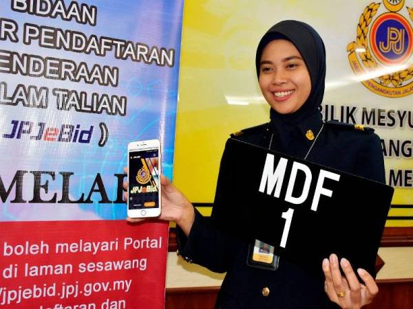 Pembantu Penguatkuasa Ibu Pejabat Jabatan Pengangkutan Jalan, Nor Hayati Zainudin menunjukkan nombor plat kenderaan MDF 1 yang akan dibuka untuk bidaan selepas sidang media bidaan Siri MDF Melalui Aplikasi JPJeBid di Pejabat JPJ Melaka hari ini. - Foto Bernama