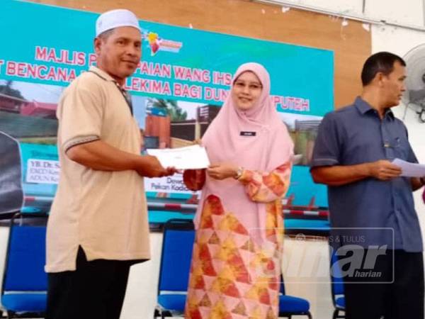 Dr Salmee (dua dari kanan) menyampaikan sumbangan wang ihsan kepada seorang mangsa ribut berkenaan.