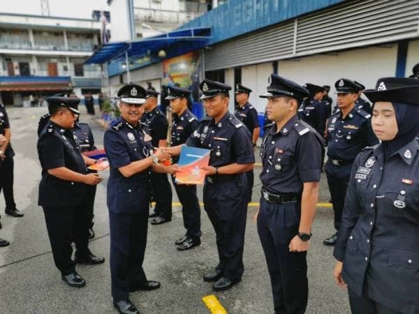 Razarudin (dua dari kiri) menyampaikan sijil penghargaan kepada salah seorang anggota pada Perhimpunan Bulanan Polis Kontinjen Perak hari ini.