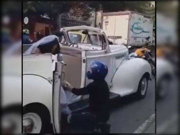 Penunggang yang berpakaian hitam dengan topi keledar berwarna biru, berjalan ke arah kenderaan pengantin perempuan dan membuka pintu kereta antik dan berlutut merayu agar dia tidak meneruskan upacara perkahwinan. - Foto Agensi