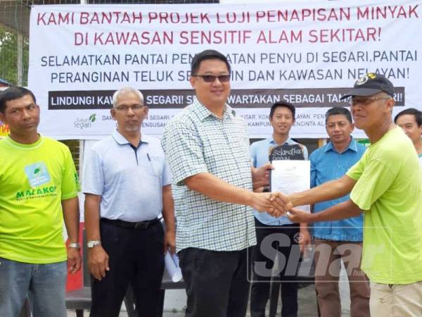 Meor Razak (kanan) menyerahkan memorandum selamatkan kawasan nelayan dan pantai pendaratan penyu Segari kepada wakil kerajaan.