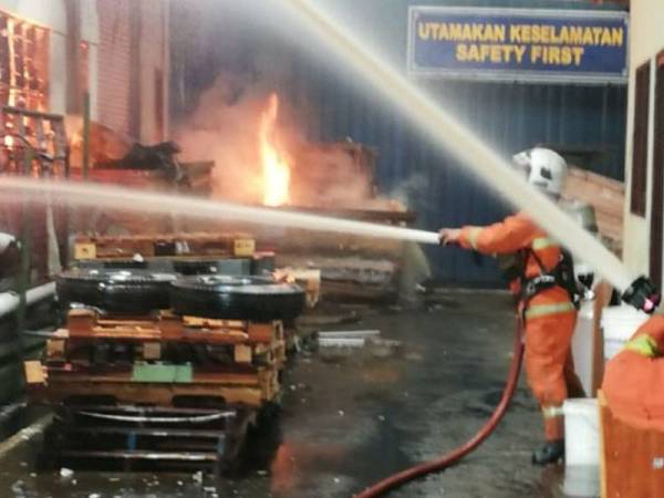 Anggota bomba bertungkus-lumus memadam kebakaran kilang terbabit sebelum api berjaya dikawal bagaimanapun 80 peratus struktur bangunan berkenaan musnah terbakar. Foto: Ihsan bomba 