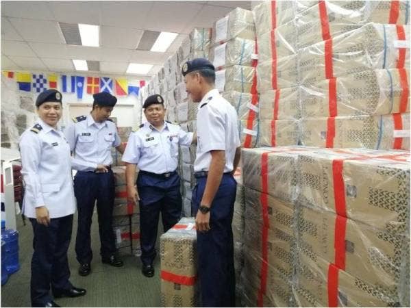 Mohammad Rosli (dua dari kanan) menunjukkan antara rokok yang dirampas dalam Operasi Patkor Optima dalam operasi di jarak 3.2 batu nautika dari Tanjung Gabang Khamis lalu.