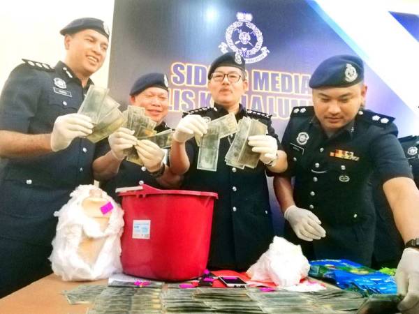 Mazlan (tiga dari kiri) menunjukkan duit mata wang asing palsu yang dirampas susulan tertangkapnya sepasang kekasih warga Afrika di sebuah premis Jalan Taman Ria, Taman Gembira Kuala Lumpur Selasa lalu.