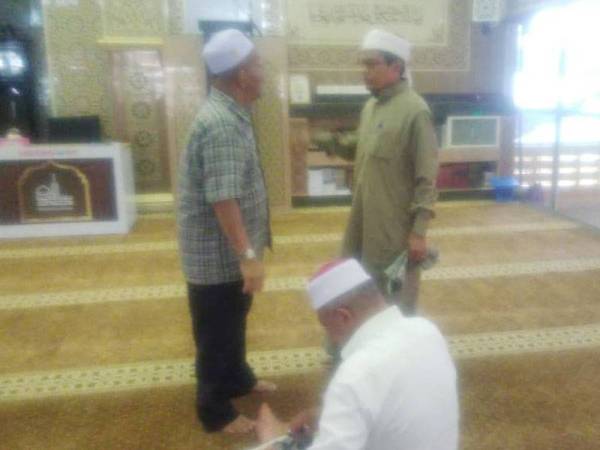 Miswan (kiri) sedang berbual dengan seorang kariah di sebuah masjid di Taman Medan.