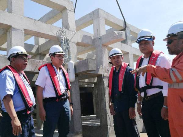 Tze Tzin (tengah) bersama Ketua Pengarah Jabatan Perikanan Malaysia, Datuk Munir Mohd Nawi (tiga dari kanan) mendengar penerangan pihak kontraktor berhubung proses menurunkan tukun rekreasi di kawasan Pulau Lima di sini semalam.