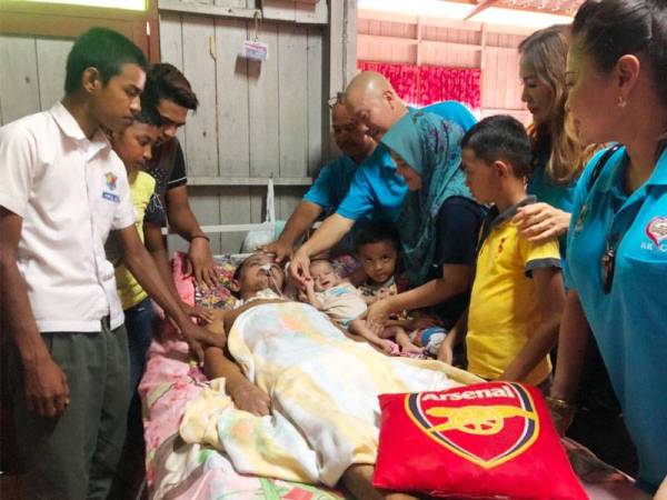 Tiong Lam (dua dari kanan), Zuraida dan enam anak mereka melihat keadaan Mat Nasir yang terlantar di atas sebuah katil di ruang tamu rumah.