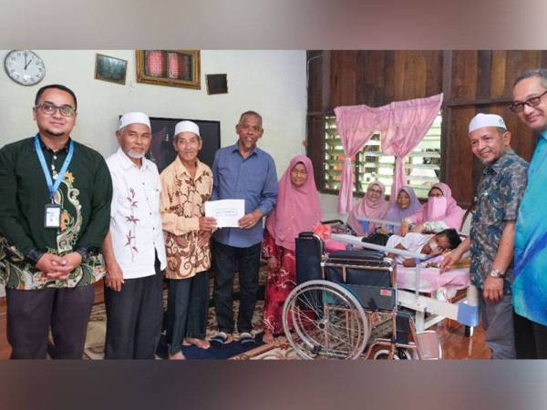 Hanafiah (tengah) menyampaikan sumbangan kepada Idris yang kini menggalas tanggungjawab menjaga tujuh cucunya. 