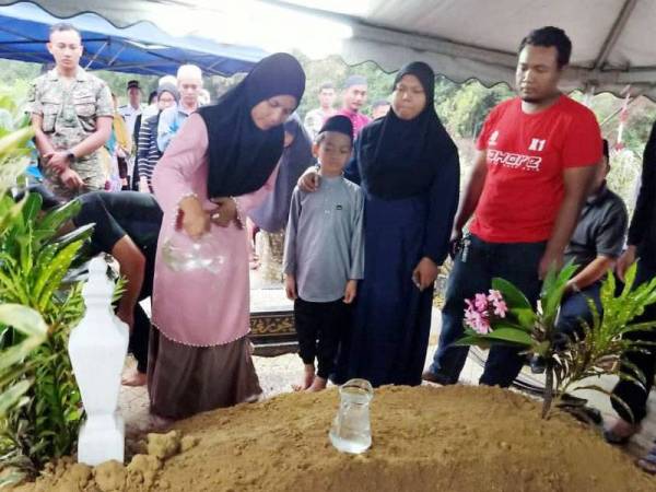 Isteri Allahyarham Siti Salbiah menyiram air di pusara suaminya.
