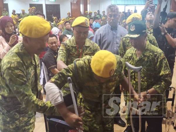 Muhyiddin (kanan) menyerahkan tongkat kepada anggota Rela ketika Majlis Rela Bersama Pemimpin di Dewan Jubli Intan, Sultan Ibrahim di sini hari ini.