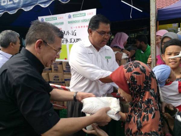 Pengurus Besar Econsave Cash & Carry, Mas Imran Adam mengiringi Salahuddin (kiri) mengagihkan 1,000 bungkus tepung gandum percuma kepada pengunjung BPR yang hadir di Serkat semalam.
