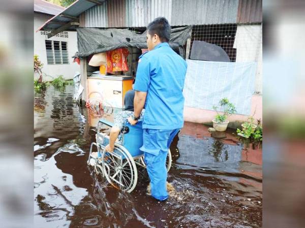 Anggota Angkatan Pertahanan Awam Malaysia (APM) membantu memindahkan seorang mangsa banjir di Changkat Jong hari ini.
