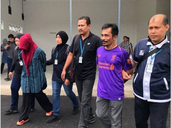 Mahussin (dua dari kanan) dan Mafuzah (lima dari kanan) dikawal sepasukan polis keluar dari lokap Kompleks Mahkamah Tunjong selepas didakwa hari ini.