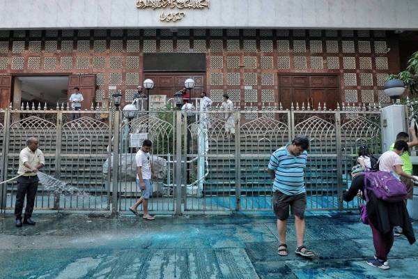 Beberapa penduduk turut membantu membersihkan kesan pewarna biru di hadapan pintu masuk Masjid Kowloon tersebut. - Foto AFP