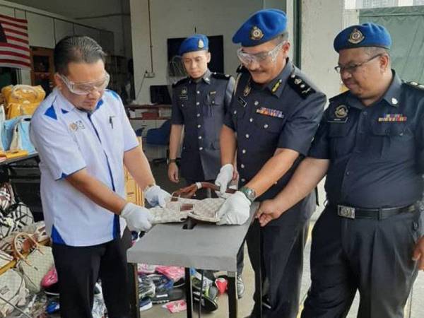 Muhamad Zikril (kiri) ketika program pelupusan barang tiruan di stor penyimpanan ekshibit Selangor di Bukit Raja hari ini.