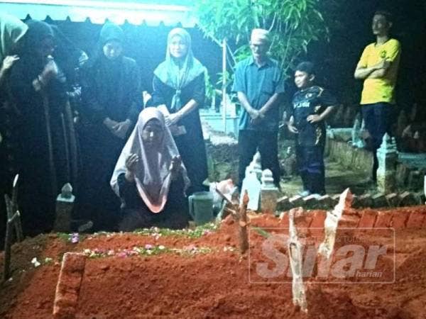 Ibu mangsa, Fatimah Latiff berdoa di tepi pusara anak dan cucunya di Tanah Perkuburan Islam Cheng Setia di sini, tadi.