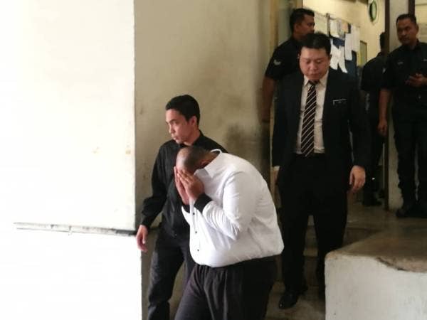 Suspek diiringi pegawai SPRM keluar dari lokap mahkamah selepas perintah reman dikeluarkan.