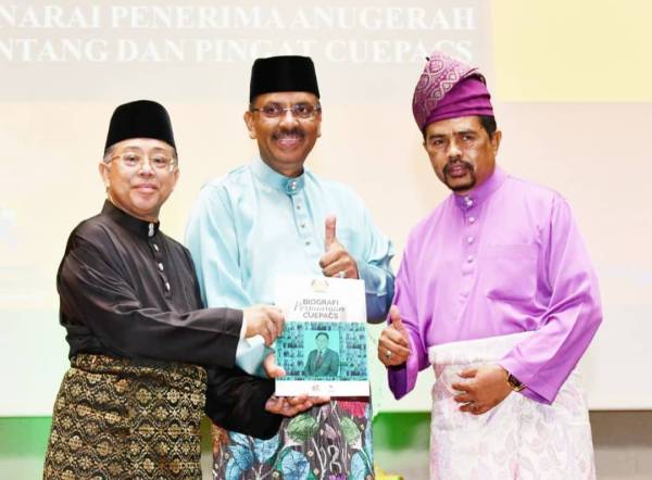 Ali (tengah) melancarkan buku Biografi Perjuangan Cuepacs sambil disaksikan Azih (kiri) dalam Majlis Makan Malam sempena Ulang Tahun Ke-62 Cuepacs di sini malam ini.